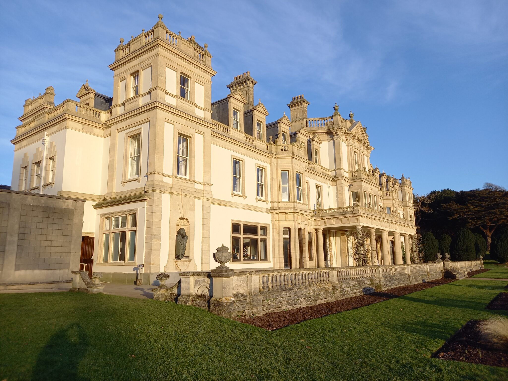 A large edwardian mansion kind of glowing against the clear blue sky.