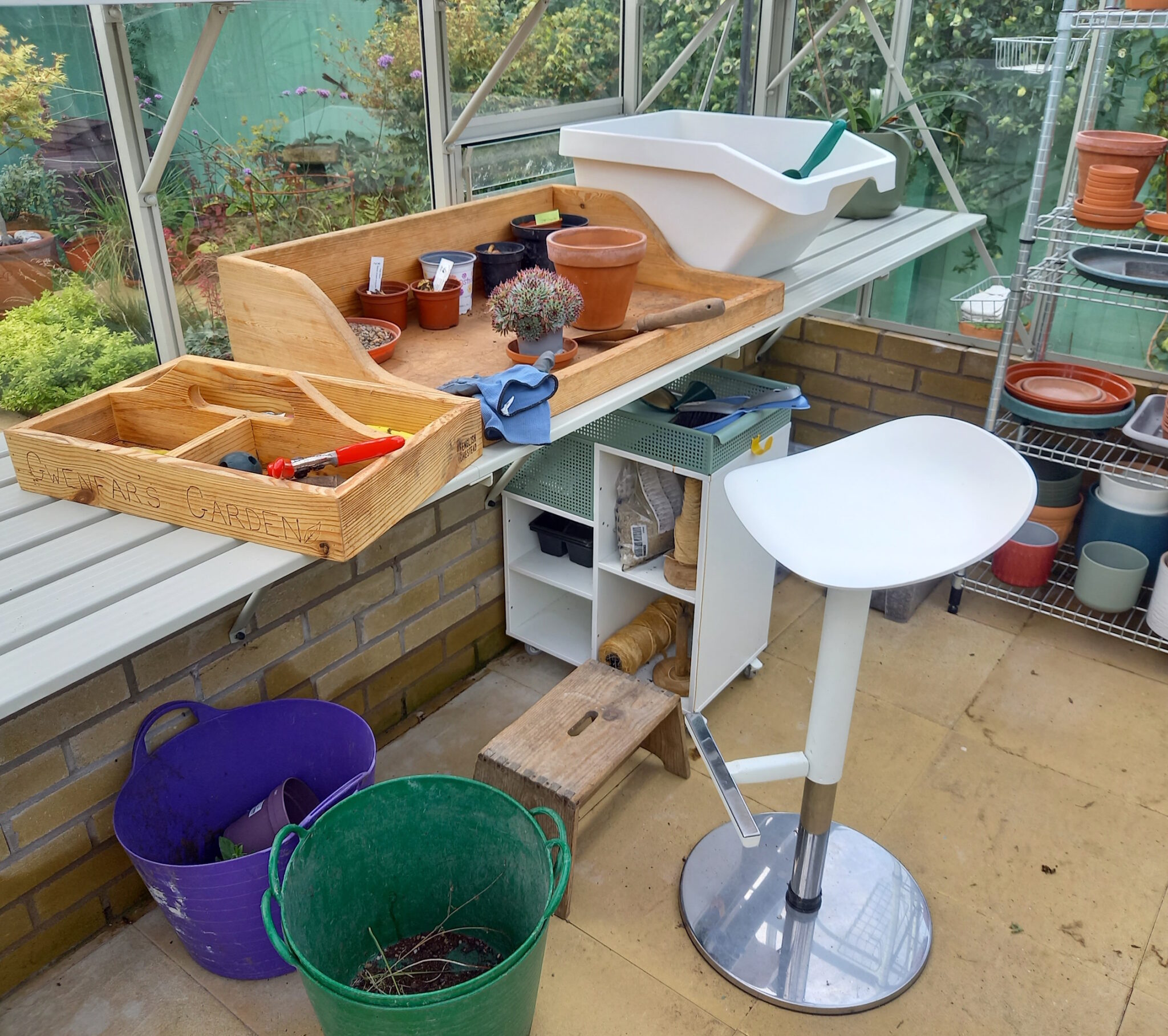 The potting bench in the greenhouse is set up to easily manage potting and tending alpines.